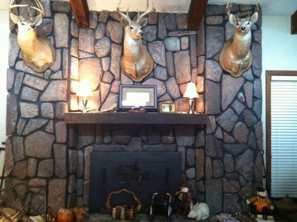 Three mounted buck heads above a stone fireplace in the family home.