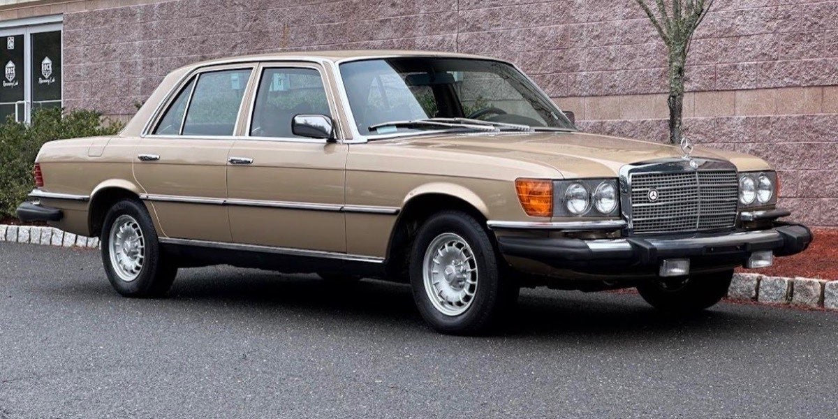 Mama's gold Mercedes sedan parked beside a brick wall.
